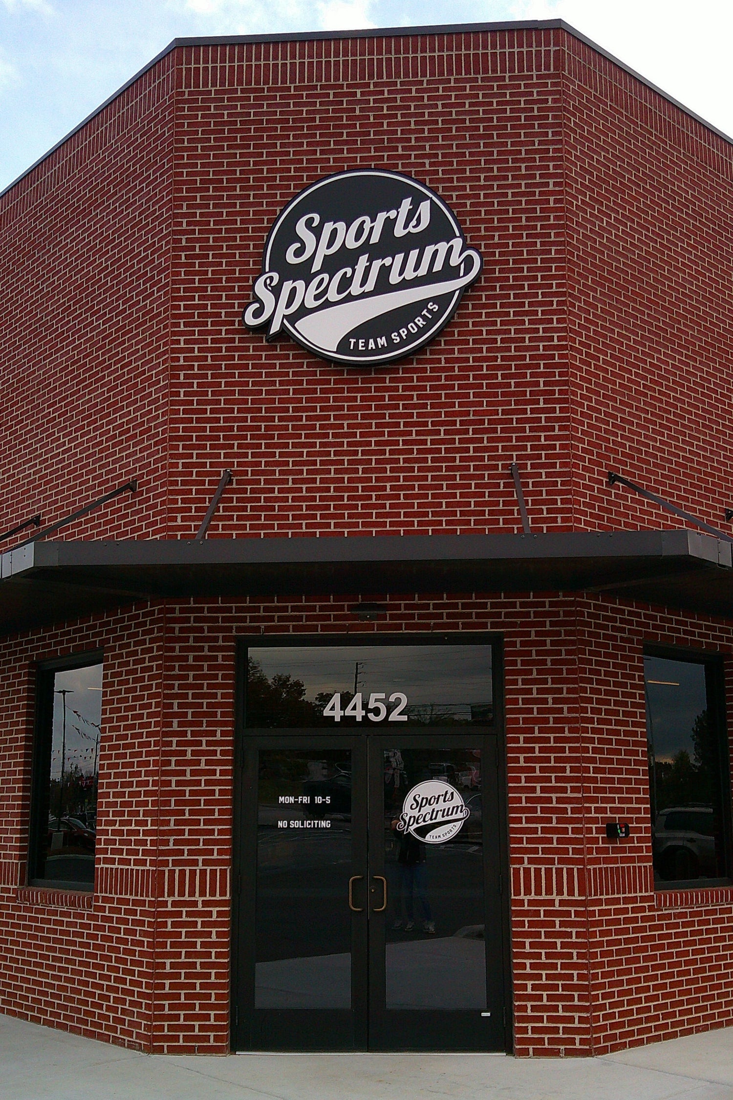 Brick building with Sports Spectrum logo on a clear day